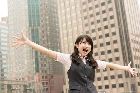 Exciting business woman raised hand in outside of city.の写真素材
