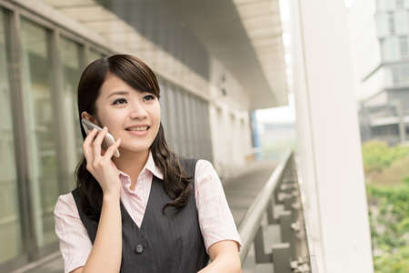 Business woman of Asian talk on cellphone, closeup portrait in urban.の写真素材