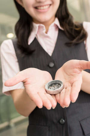 Business woman holding a compass, closeup portrait in city.の写真素材