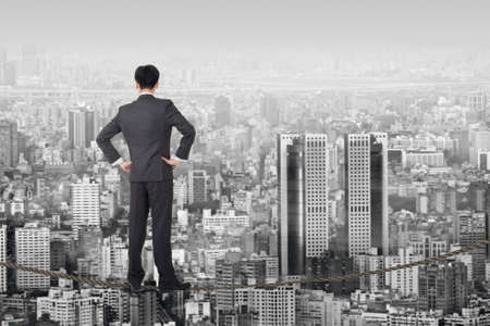 Chinese business man stand on rope, manipulation  about risk, adventure, future or dream etc.の写真素材