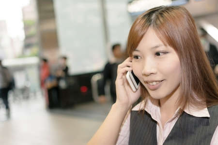 Portrait of young business woman stand and talk on mobile phone in the MRT station, Taipei, Taiwan, Asia.の写真素材