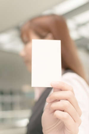 Asian business woman hold a blank business card, closeup portrait in outside of modern city.の写真素材