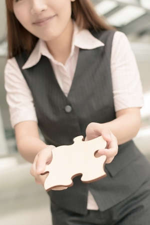 Asian business woman hold a wooden puzzle, closeup portrait in outside of office buildings.の写真素材