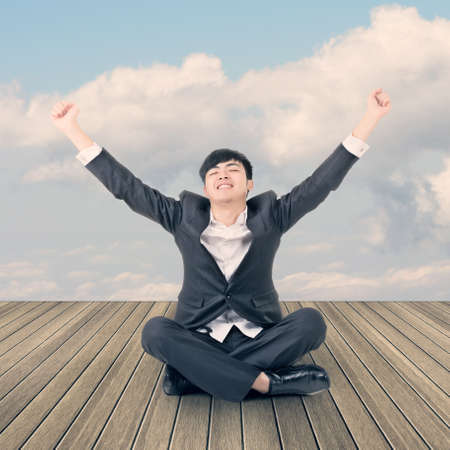 Asian business man sit on ground and open arms feel free and relax.の写真素材