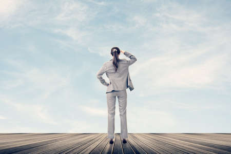 Concept of success with businesswoman standing on the wooden surface and looking ahead for the...