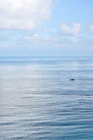White fluffy clouds blue sky above a surface of the seaの写真素材