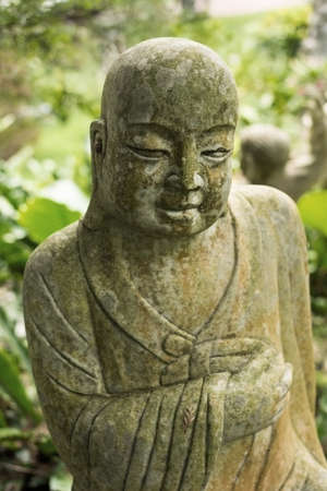 Ruined stone statue Ksitigarbha Bodhisattva in garden.
