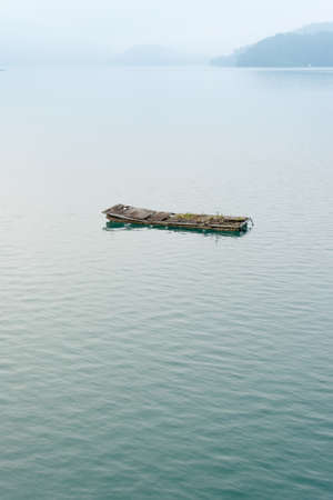 Landscape of famous Sun Moon Lake in the morning with a boat and mist in Taiwan, Asia.の写真素材