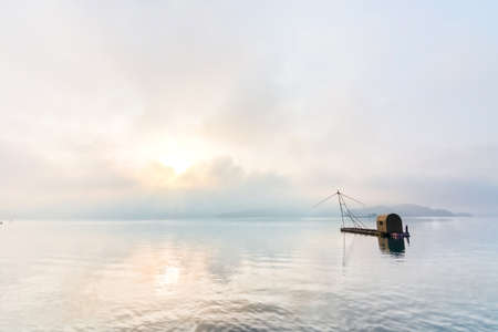 Landscape of famous Sun Moon Lake in the morning with a boat and mist in Taiwan, Asia.の写真素材