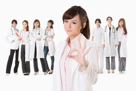 Asian doctor woman stand in front of her team and give you an ok sign, closeup portrait on white background.の写真素材