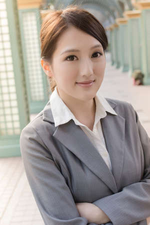 Young pretty Asian business woman portrait,  standing in front of modern buildings.の写真素材
