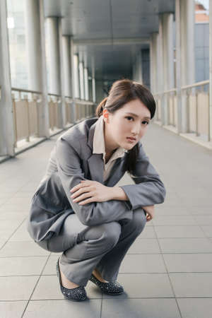 Business woman feel sad and squat on ground look at you in city.の写真素材