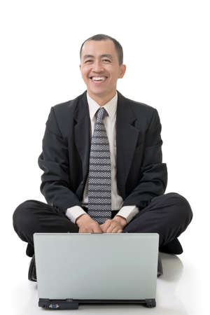 Smiling business man of Asian sit and use laptop on ground, full length on white background.の写真素材