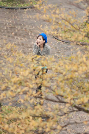 Cheerful Asian lady talking on cellphone at street in the park, Taipei, Taiwan.の写真素材
