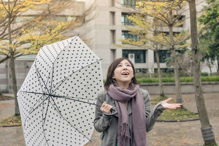 Happy smiling Asian woman holding an umbrella when rains stopped in city.の写真素材