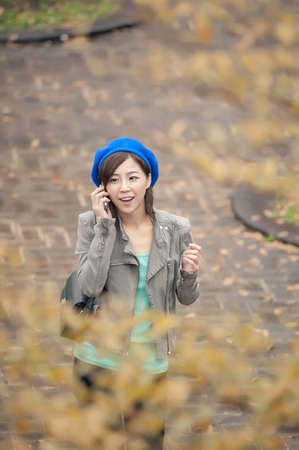 Cheerful Asian lady talking on cellphone at street in the park, Taipei, Taiwan.の写真素材