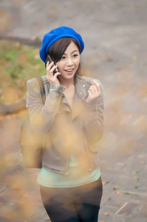 Cheerful Asian lady talking on cellphone at street in the park, Taipei, Taiwan.の写真素材