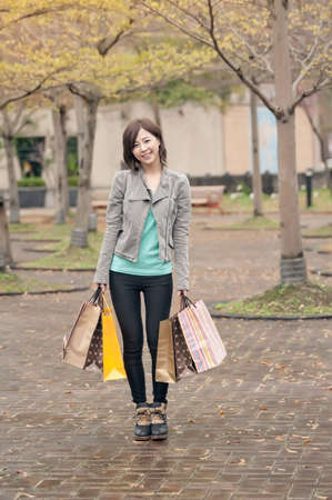 Happy smiling shopping woman holding bags in the street.の写真素材