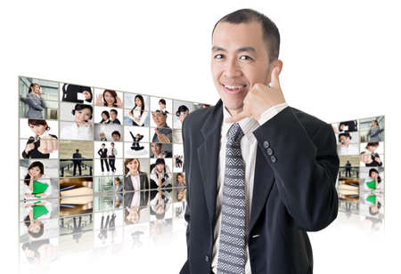 Asian business man or boss standing in front of tV screen wall showing pictures of business concept.の写真素材