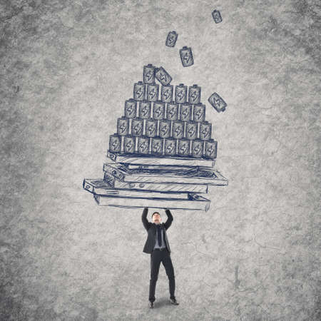 Young man holding mobile phones and batteries, concept of energy waste, power, technology problems etc.の写真素材