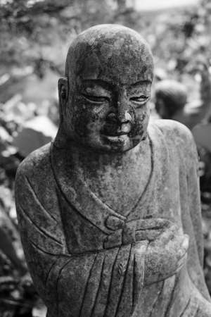 Ruined stone statue Ksitigarbha Bodhisattva in garden.の写真素材