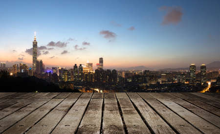 City skyline in night with famous 101 skyscraper and buildings in Taipei, Taiwan. Focus on wooden floor.の写真素材