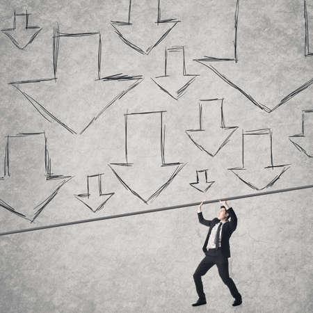 Asian business man raising hands against arrows, concept of stress.の写真素材