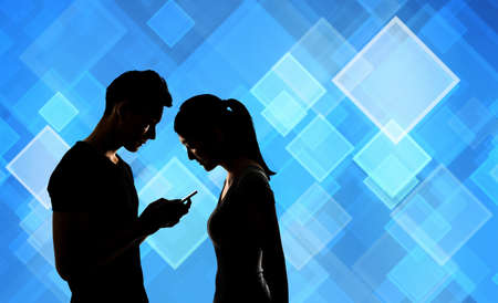 Couple using cellphone, silhouette portrait.