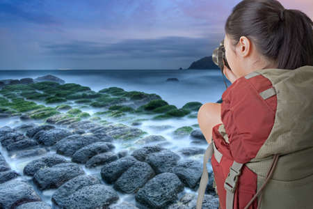 Asian female backpacker take photo at the coastline