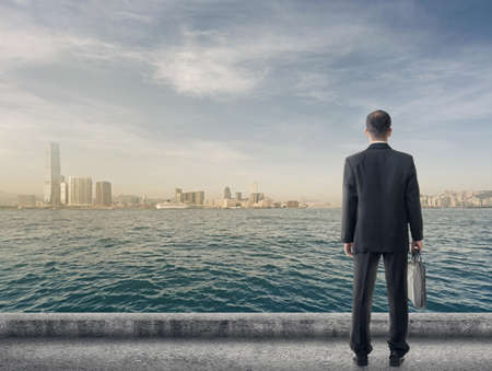 Asian business man stand and look the city under sky, concept of hard work, business, future etc.の写真素材