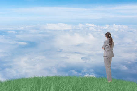 Asian business woman standing on grassland and thinking with copyspace on heaven.の写真素材