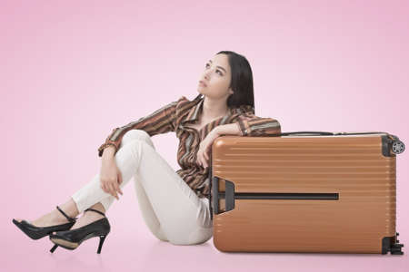 Modern Asian woman sit on ground with a luggage.の写真素材