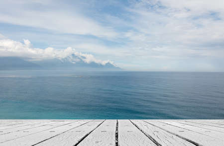 Empty wooden deck table with copyspace under sunny cloudy sky in the beach, focus on the wooden...