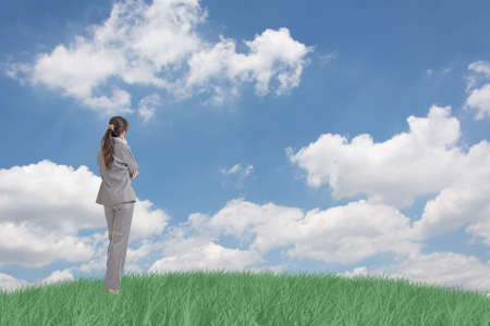 Asian business woman standing on grassland and thinking with copyspace on heaven.の写真素材