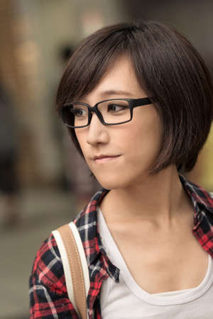 Closeup portrait of young Asian woman looking with peace and blue stand in outdoor street.の写真素材