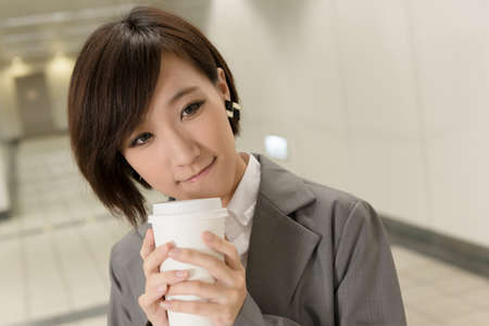 Asian young business woman holding cup of coffee in modern building.の写真素材