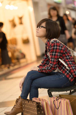 Shopping young girl of Asian sit at bench at mall in Taipei, Taiwan.の写真素材