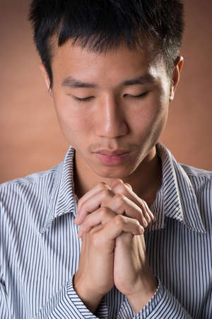 Young Chinese frank businessman praying, closeup portrait in studio.