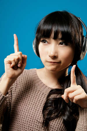 Asian girl listen music on studio blue background.の写真素材