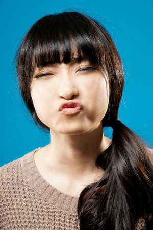 Funny Asian beauty, closeup portrait on studio blue background.の写真素材