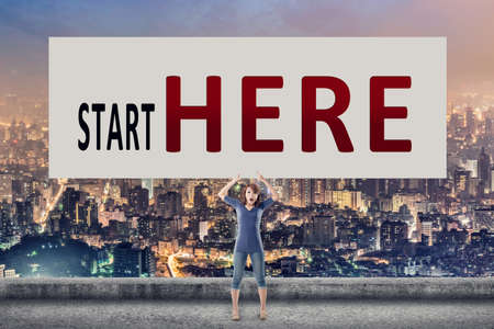 Start here, words on blank board hold by a young girl in the outdoor.の写真素材