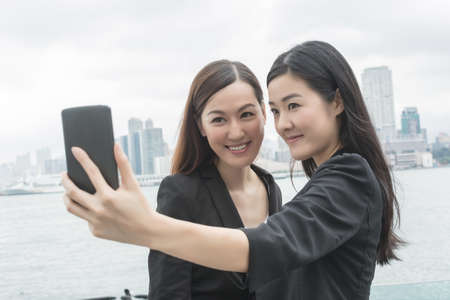 Asian business women take a selfie in the city.
