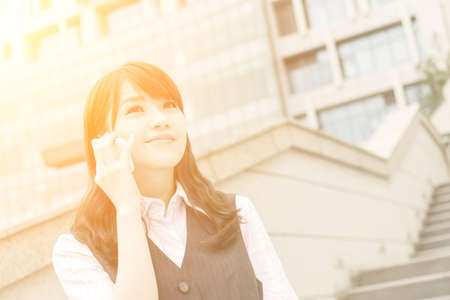 Business woman of Asian talk on cellphone, closeup portrait in urban.の写真素材