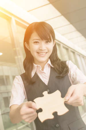 Business woman holding a piece of puzzle, closeup portrait in city.の写真素材