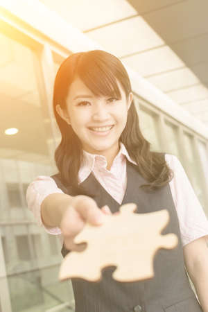 Business woman holding a piece of puzzle, closeup portrait in city.の写真素材