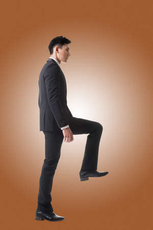 Asian businessman walking up on stairs, full length portrait isolatedの写真素材