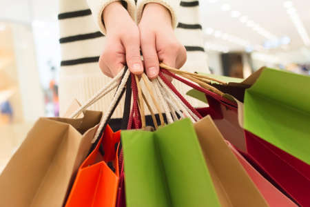 holding shopping bags in various colours, closeupの写真素材