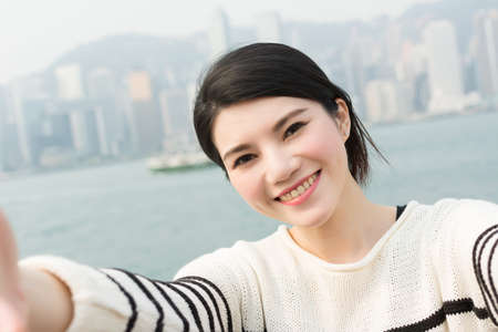 Young Asian woman take a selfie at Victoria Harbor, Hong Kong.の写真素材