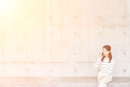 Woman pick up a call with copyspace on wallの写真素材