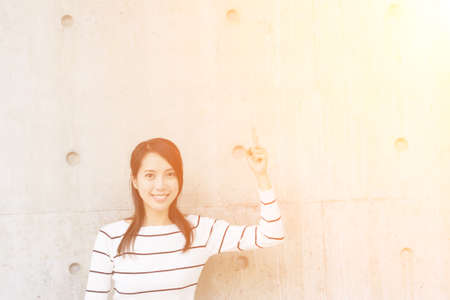 Woman thinking against concrete wall
